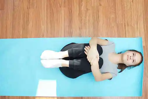 young woman feeling relaxed as doing stretching exercise on a yoga mat